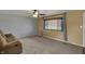 Comfortable living room features neutral paint, plush carpet, large windows, and a cozy sofa for relaxing at 1585 S 600 W, New Palestine, IN 46163