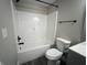 Clean bathroom featuring a white bathtub, toilet, and gray walls at 1809 S H St, Elwood, IN 46036