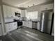 Modern kitchen featuring white cabinets, stainless steel appliances, and gray wood-look flooring at 1809 S H St, Elwood, IN 46036