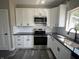 Well-lit kitchen showcases white cabinetry, black granite countertops, and stainless steel appliances at 1809 S H St, Elwood, IN 46036