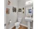Bright half bathroom features a pedestal sink, wood-look flooring, and charming wall decor at 1842 Central Ave, Indianapolis, IN 46202