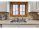 Granite countertops surround stainless steel kitchen sink below window with wood trim at 222 Wellington Pkwy, Noblesville, IN 46060