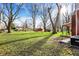 Spacious backyard featuring mature trees, green grass, and a detached outbuilding at 333 E Waterbury Rd, Indianapolis, IN 46227