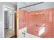 A view of pink tiled walls, a shower head, and white trim in a bathroom with a glimpse into a hallway at 333 E Waterbury Rd, Indianapolis, IN 46227