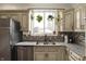 Well-lit kitchen featuring stainless steel appliances, a granite countertop, and a window with hanging plants at 3535 Birchwood Ave, Indianapolis, IN 46205