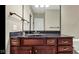 Bathroom vanity featuring wood cabinets, dark countertop, and undermount sink with bronze fixtures and mirror at 3629 Pete Dye Blvd, Carmel, IN 46033