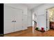Bright hallway with hardwood floors, white trim, and doorway into powder room at 3629 Pete Dye Blvd, Carmel, IN 46033