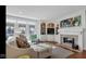Comfortable living room with hardwood floors, a fireplace, a built-in entertainment center, and ample natural light at 3629 Pete Dye Blvd, Carmel, IN 46033