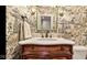 Charming powder room with patterned wallpaper, wooden vanity, and green-framed mirror at 3629 Pete Dye Blvd, Carmel, IN 46033