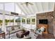 Bright sunroom featuring a ceiling fan, comfortable seating, lake views, brick accent wall, and tiled flooring at 3862 Penzance Pl, Carmel, IN 46032