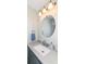 Bathroom showcasing a round mirror, sink with stylish fixtures, and a vanity with a gray countertop at 4414 Lexington Ave, Indianapolis, IN 46203