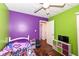 Bright bedroom with a ceiling fan, hardwood floors, and playful purple and green color scheme at 4414 Lexington Ave, Indianapolis, IN 46203