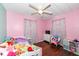 Cozy bedroom with plush toys, pink walls, wood floor and ceiling fan, creating a warm, inviting space at 4414 Lexington Ave, Indianapolis, IN 46203