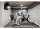 Unfinished basement gym with treadmill, stationary bike, free weights, and wall-mounted television at 4850 Guilford Ave, Indianapolis, IN 46205