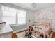 Charming room with floral wallpaper, a wooden rocking chair, and a white crib at 4850 Guilford Ave, Indianapolis, IN 46205