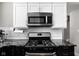 Close up of a sleek black gas stove with white subway tile backsplash and black countertops at 4850 Guilford Ave, Indianapolis, IN 46205