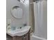 Compact bathroom featuring a white vanity, a round mirror, and a tub-shower combination, maximizing space and functionality at 5110 Chelsea Rd, Indianapolis, IN 46241