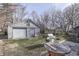 View of a gray garage and backyard with grill, wooden spool table, and bare trees in the winter at 5110 Chelsea Rd, Indianapolis, IN 46241