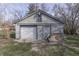 View of gray garage with a closed white garage door, a side door, and assorted items stacked nearby at 5110 Chelsea Rd, Indianapolis, IN 46241