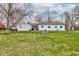 Lush backyard with a well-maintained lawn, mature trees, and a view of the home's exterior at 5902 Sunset Dr, Indianapolis, IN 46239