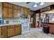 Kitchen with wood cabinetry, white appliances, and unique pantry doors at 5902 Sunset Dr, Indianapolis, IN 46239