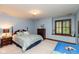 Cozy bedroom with blue walls, wooden furniture, and a window seat overlooking the yard at 6010 Fawnwood Dr, Greenwood, IN 46143