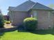 Brick home exterior showcasing meticulous landscaping with green lawn, trimmed bushes, and a visible AC unit at 6010 Fawnwood Dr, Greenwood, IN 46143
