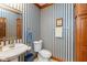 Charming powder room with blue striped wallpaper, pedestal sink, and wooden trim at 6010 Fawnwood Dr, Greenwood, IN 46143