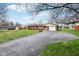Inviting brick home with attached garage, a long driveway, and a well-maintained green lawn at 6905 E Hanna Ave, Indianapolis, IN 46203