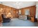 Cozy living room with wood paneled walls, comfortable seating, and seamless access to the kitchen at 6905 E Hanna Ave, Indianapolis, IN 46203