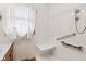 Modern shower featuring a built-in seat, grab bars, and pristine white tile finish at 6905 E Hanna Ave, Indianapolis, IN 46203