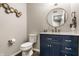 Modern bathroom with a sleek blue vanity, marble countertop, round mirror and elegant gold fixtures at 9449 Maple Way, Indianapolis, IN 46268