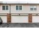 Townhome exterior with three garage doors, brick accents, and light colored siding at 9449 Maple Way, Indianapolis, IN 46268