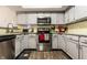 Bright kitchen boasts gray cabinets, stainless steel appliances, granite countertops and warm wooden floors at 9449 Maple Way, Indianapolis, IN 46268