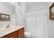 A clean bathroom with wood vanity, framed mirror, and a shower with white curtain at 1160 Falcon Rdg, Carmel, IN 46280