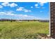 Brick exterior and large grassy field surrounded by trees and other houses under a clear blue sky at 1347 Shaw Ln, Shelbyville, IN 46176