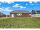 View of the brick exterior and back yard under a clear blue sky, next to a grassy field at 1347 Shaw Ln, Shelbyville, IN 46176