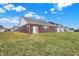View of the brick exterior and back yard under a clear blue sky, next to a grassy field at 1347 Shaw Ln, Shelbyville, IN 46176
