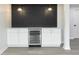 Finished basement wet bar with white cabinets, beverage fridge, striking black backsplash, and modern pendant lighting at 1351 Sullivans Rdg, Zionsville, IN 46077