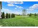 Expansive backyard with lush green grass, manicured evergreens, and a scenic pond with fountain views at 15752 Matthews Ln, Noblesville, IN 46060