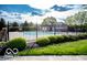 Community pool area featuring a black metal fence, a clubhouse, and manicured landscaping at 15898 Bounds Dr, Noblesville, IN 46062