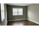 Comfortable bedroom featuring gray walls, wood-look flooring, white trim, and two windows with white blinds at 1904 S Rosemont Ave, Muncie, IN 47302
