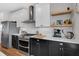 Well-appointed kitchen featuring stainless steel appliances, white cabinets, modern backsplash, and wood shelving at 1945 Carrollton Ave, Indianapolis, IN 46202