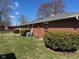 The back of the property has a brick exterior, small bushes and green grass in the backyard at 2309 Dover St, Anderson, IN 46013