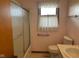 Functional bathroom with a frosted sliding shower door, toilet, and a window with blinds at 2309 Dover St, Anderson, IN 46013