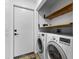 Laundry room area featuring a washer, dryer, wooden shelving, and white door at 310 E St Clair St, Indianapolis, IN 46202