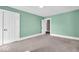 Empty bedroom with green walls, neutral carpeting, and two white doors at 3345 Ruckle St, Indianapolis, IN 46205