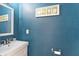Cozy powder room with blue textured walls, a white vanity, and a decorative framed picture at 3345 Ruckle St, Indianapolis, IN 46205