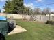 Backyard area with green lawn, bordered by a wood fence with trees, and a small patio at 3760 Briar Hill Way, Columbus, IN 47203