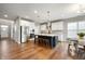 Open-concept kitchen with stainless steel appliances, white cabinets, and hardwood floors leading to dining area at 4241 Risen Star Way, Bargersville, IN 46106